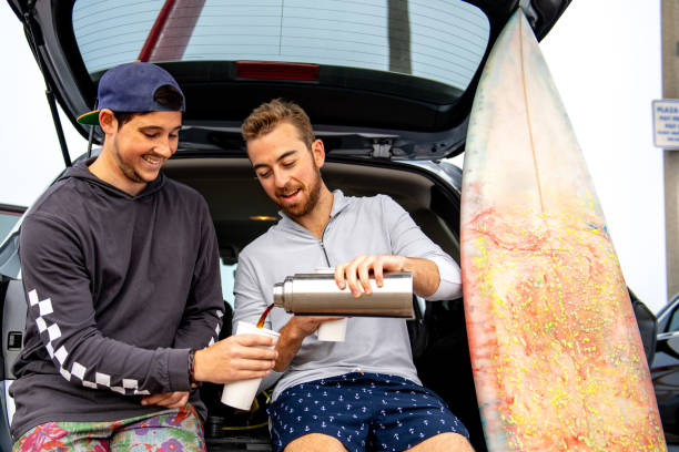 istock Two Surfers Sit On Car and Pour a Coffee Before Surfing 1144659342
