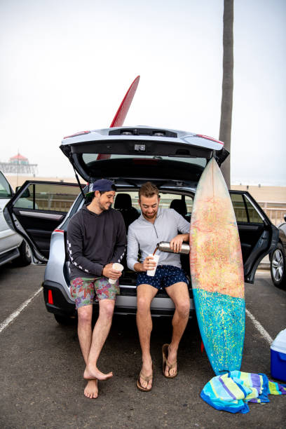서핑을 하기 전에 두 개의 서퍼가 차에 앉아서 커피를 부 어 줍니다. - motor vehicle road trip western usa southern california 뉴스 사진 이미지