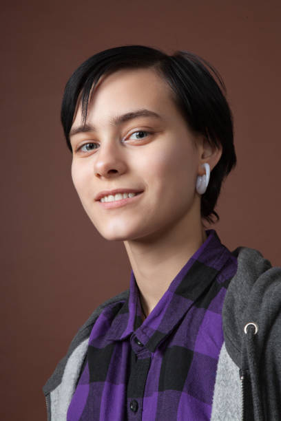 studio portrait of an attractive 18 year old woman with short hair on a brown background. - earring human face brown hair black hair imagens e fotografias de stock