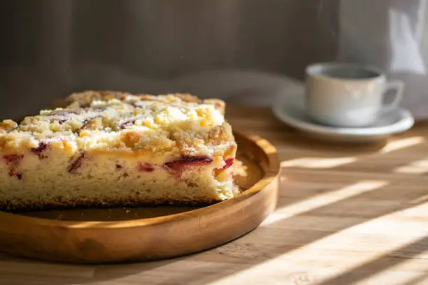 And about the red plum (cake inspired by the Streuselkuchen of German origin, also called Cuca and Cuque in Brazil). With cup of coffee, arranged in rustic wood, strong shadows and area for writing.