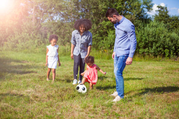 семья на открытом воздухе летом играет в футбол в парке - family with two children family park child стоковые фото и изображения