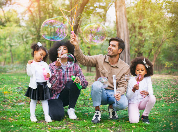 istock Happy family playing soap bubbles in park. 1144668239