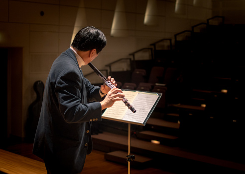 Senior musician playing flute at classical music concert