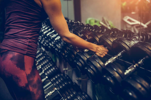 Adult woman exercising with barbell in gym