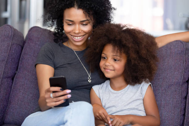 istock Cheerful mother little daughter spending time at home using smartphone 1144680155
