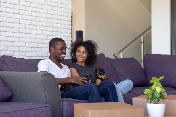 pareja de africanos milenales sentados descansando en el sofá en el día de la mudanza - moving house physical activity real estate couple fotografías e imágenes de stock