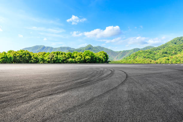 空のアスファルトレーストラックと緑の山自然景観 - car mount ストックフォトと画像