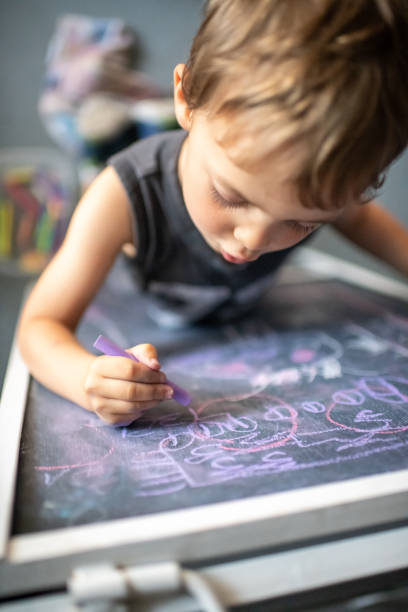 istock Three years old child little boy drawing in a blackboard 1144700337