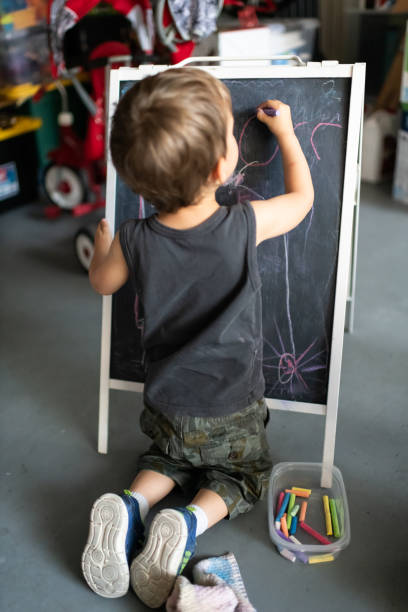 istock Three years old child little boy drawing in a blackboard 1144700945