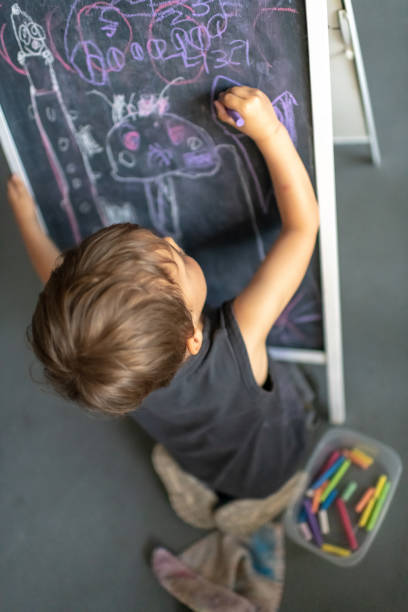 istock Three years old child little boy drawing in a blackboard 1144700959