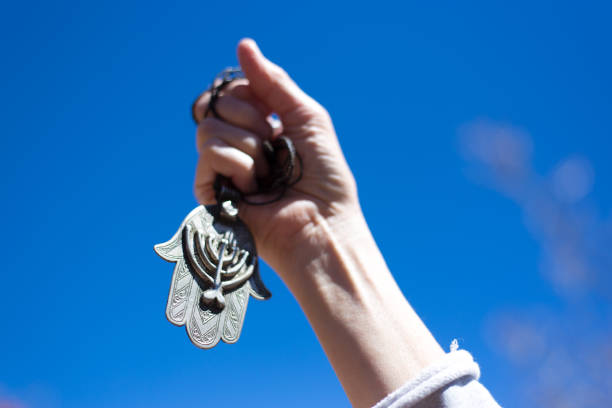 Close-up of human hand holding old pocket watch on light background