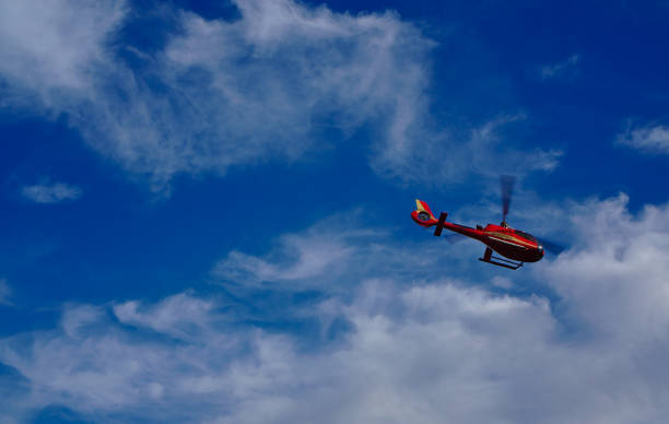 istock Red helicopter flying with blue sky and white clouds in background 1144712519