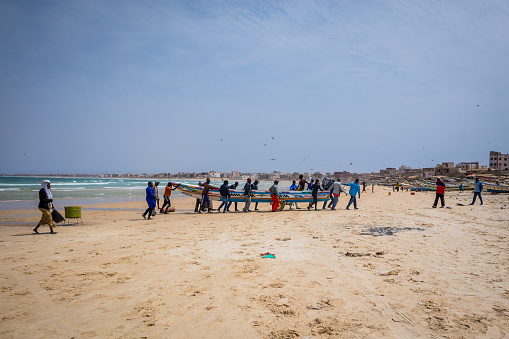 DAKAR, SENEGAL, FEBRUARY 18 2017:  A group of local fishermen pulling the rope with fishing net out of the water on the picturesque beach of Yoff in Senegal, Africa.