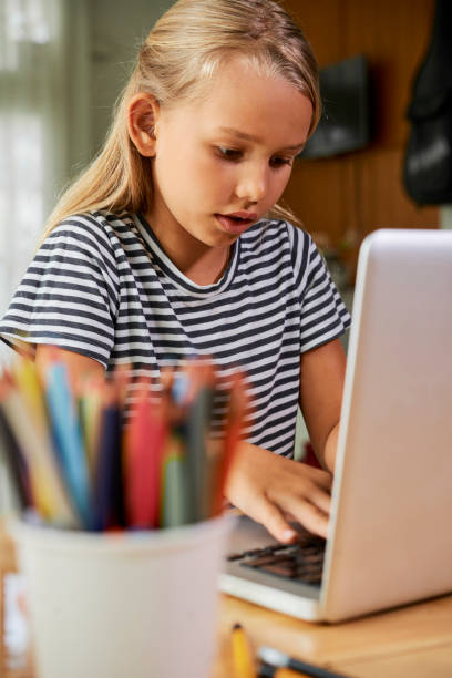 istock Schoolgirl working on laptop at home 1144723080