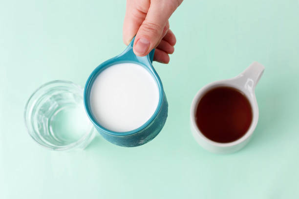 istock Multicolored mugs with hot drinks and female hand on a blue background, top view 1144728374