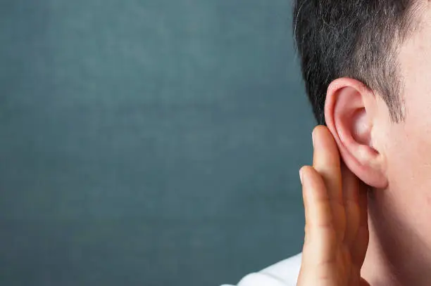 Photo of The man listens attentively with her palm to her ear, close-up, the news concept