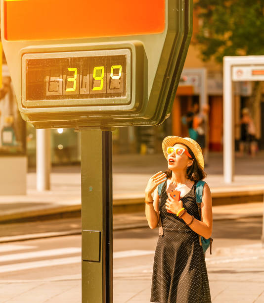 la donna soffre di calore e colpi di sole all'esterno con il caldo sullo sfondo di un termometro stradale che mostra 39 gradi celsius - heat female summer vacations foto e immagini stock