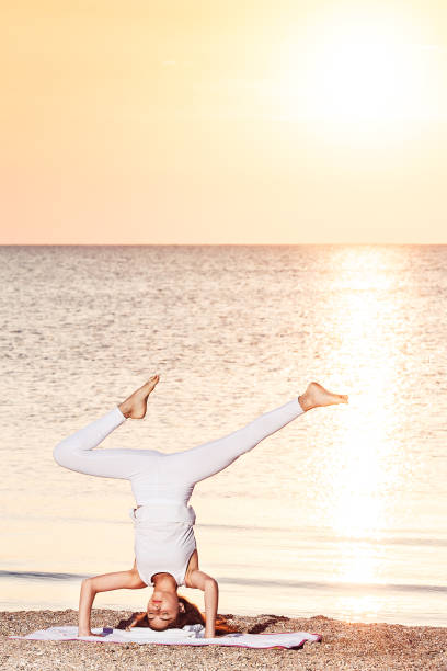 istock young girl doing yoga at sunrise on beach. 1144729650