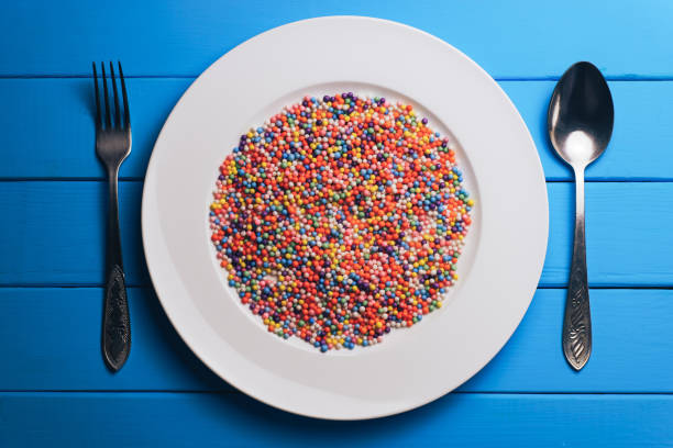 istock White plate with color preparations (vitamins, dyes, flavor enhancers, nutritional supplements, innovative technologies, candy sweets) on an blue wooden table background. 1144730641