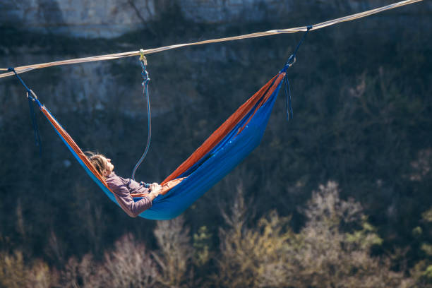 Man in hammock. Man hanging  in hammock above mountain valley gap. Slack line contest. highlining stock pictures, royalty-free photos & images