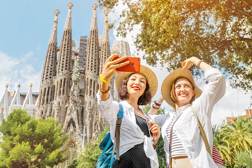 BARCELONA, España-11 de julio de 2018: chicas jóvenes amigas haciendo foto autofoto en su teléfono inteligente frente a la famosa catedral católica de la Sagrada Familia. Viaje en Barcelona Concept photo