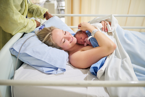 Shot of a beautiful young mother lying in bed with her newly born baby girl in the hospital