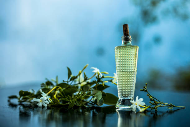 Close up of spray or perfume of Indian jasmine flower or juhi or Jasminum Auriculatum on wooden surface in a small bottle with raw flowers. stock photo