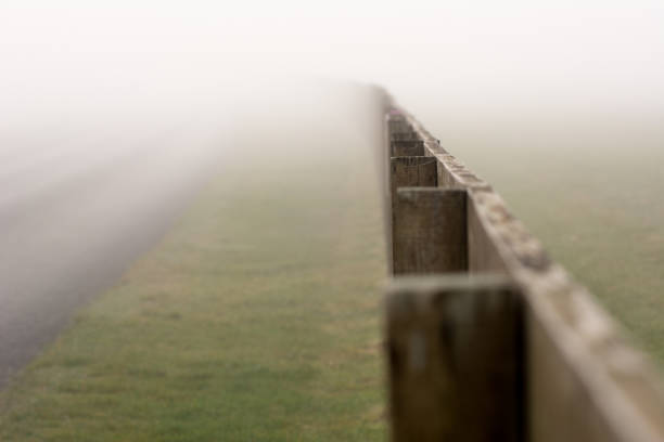 Early morning mist with wooden paddock fence dissapering into the misty distance