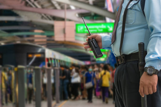 sicherheitswacht kontrolliert indoor-eingangsbahnhof, menschen stehen in linien, die auf bts-himmelszug am bahnhof siam in stoßzeiten warten - talkie stock-fotos und bilder