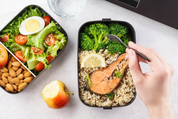 istock Man eating lunch from takeaway lunch box at working table. 1144744039