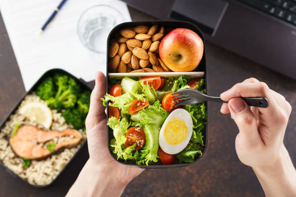 istock Man eating lunch from takeaway lunch box at working table. 1144749960
