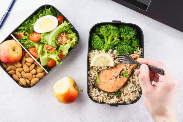 istock Man eating lunch from takeaway lunch box at working table. 1144750024
