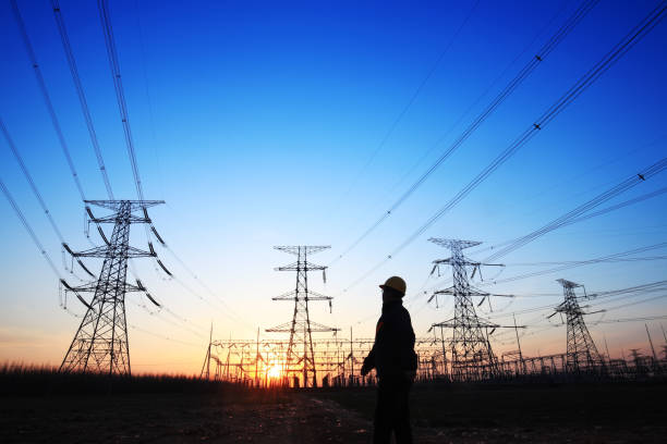istock Electricity workers and pylon silhouette 1144750173
