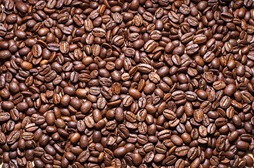 Black roasted coffee beans pattern. Abstract texture of dark arabika seeds, natural caffeine wallpaper