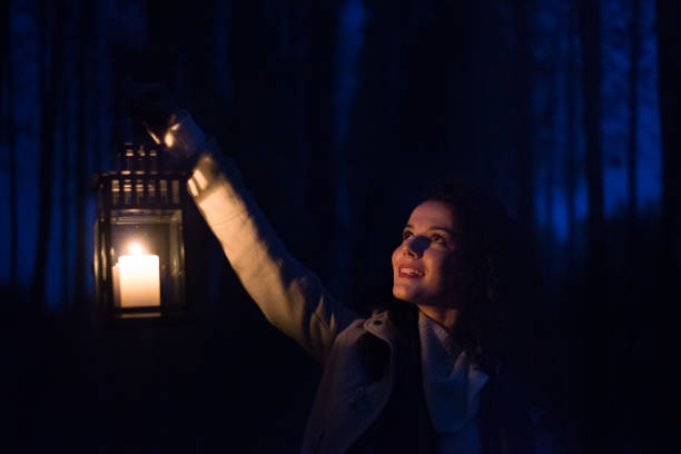 istock Woman with lantern in the woods at night 1144753628