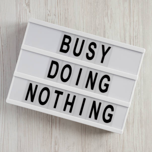 istock 'Busy doing nothing' on a modern board over white wooden surface, top view. From above, flat lay, overhead. 1144753838