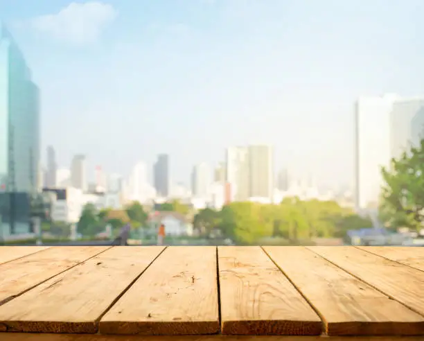 Wood table top on blur window glass,wall background with city view.For montage product display or design key visual layout