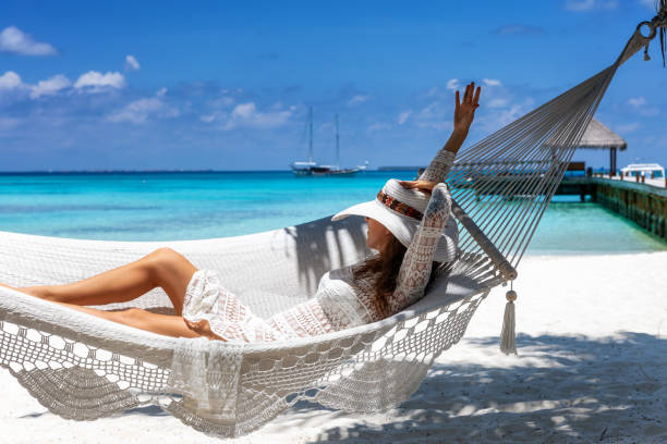 istock Woman relaxes in a hammock on a tropical beach 1144766363