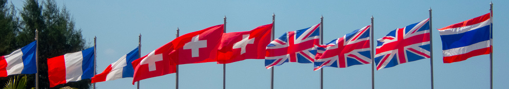 French, Swiss, UK and Thailand flags on flagpoles.