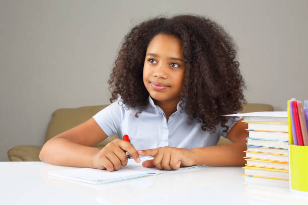 istock black school girl writes in a notebook, doing homework 1144771522