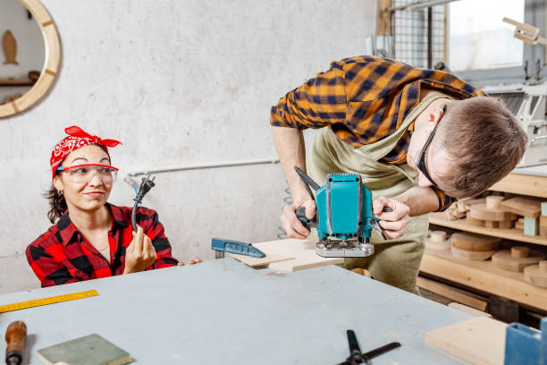 istock Male carpenter working with electric jigsaw and his girlfriend shows the plug socket. The concept of safety and humor 1144772837