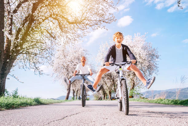 花の下の田舎道で自転車に乗ると、父と息子が楽しい。ヘルシースポーツライフスタイルコンセプトイメージ - relaxation exercise fruit bicycle mode of transport ストックフォトと画像