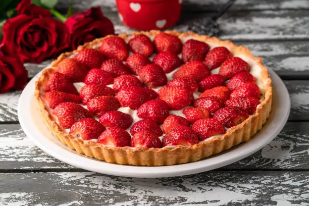 strawberry tart on a rustic old wooden grey colour backdrop, bright red colour, red roses