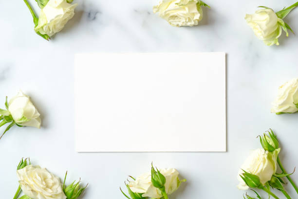 istock White rose frame and blank paper card on marble background, flat lay composition, top view, overhead. 1144777497