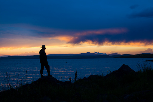 Çıldır gölünde gün batımını izleyen kovboy şapkalı adam