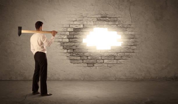 istock Business man hitting brick wall with hammer and opening a hole 1144780262