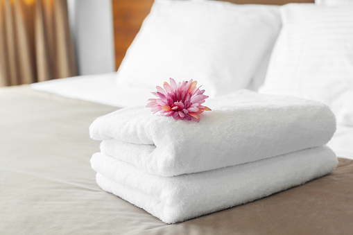 towels and flower on bed in hotel room
