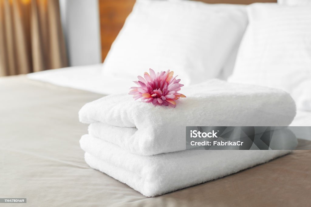 towels and flower on bed in hotel room Hotel Stock Photo