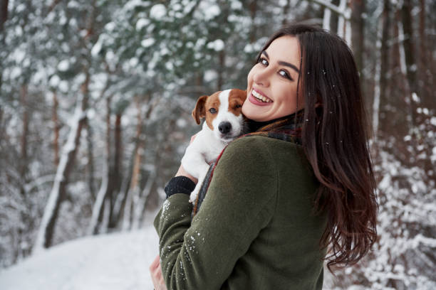 istock Girl is turned her head to the camera. Smiling brunette having fun while walking with her dog in the winter park 1144784566
