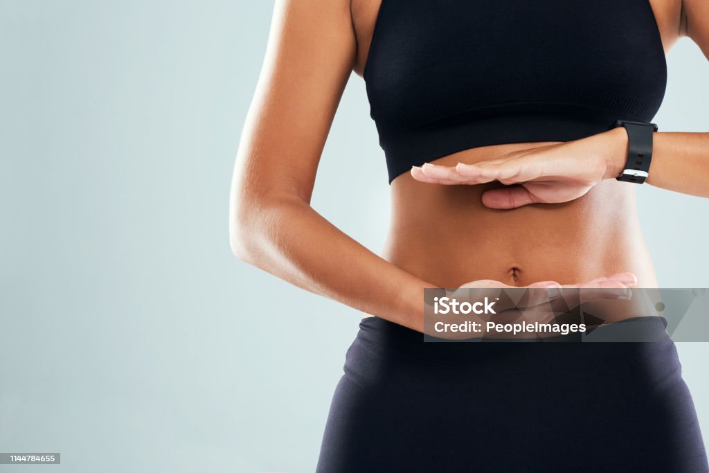 The results are already showing Studio shot of an unrecognizable sporty woman framing her stomach with her hands against a grey background Abdomen Stock Photo